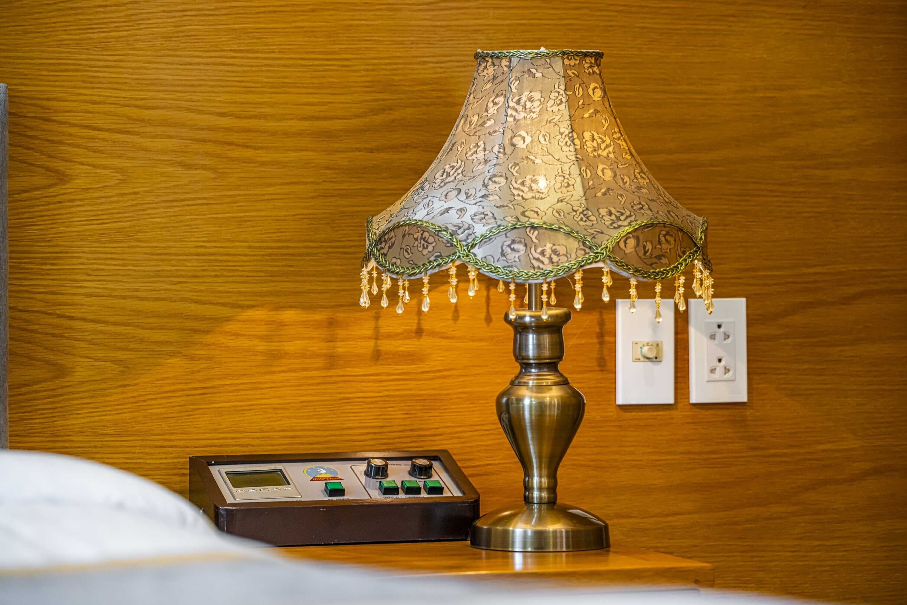 A lamp with a patterned lampshade and a control panel on a wooden surface.