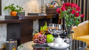 Une table ornée d’un arrangement de fruits, d’un vase de roses rouges et d’une théière.