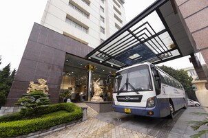 A modern building entrance with a bus parked in front.