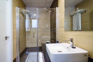 A modern bathroom with a glass-enclosed shower, a large white sink, and a mirror.