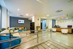Un hall de hotel con mostrador de recepción, zona de estar y una escalera.