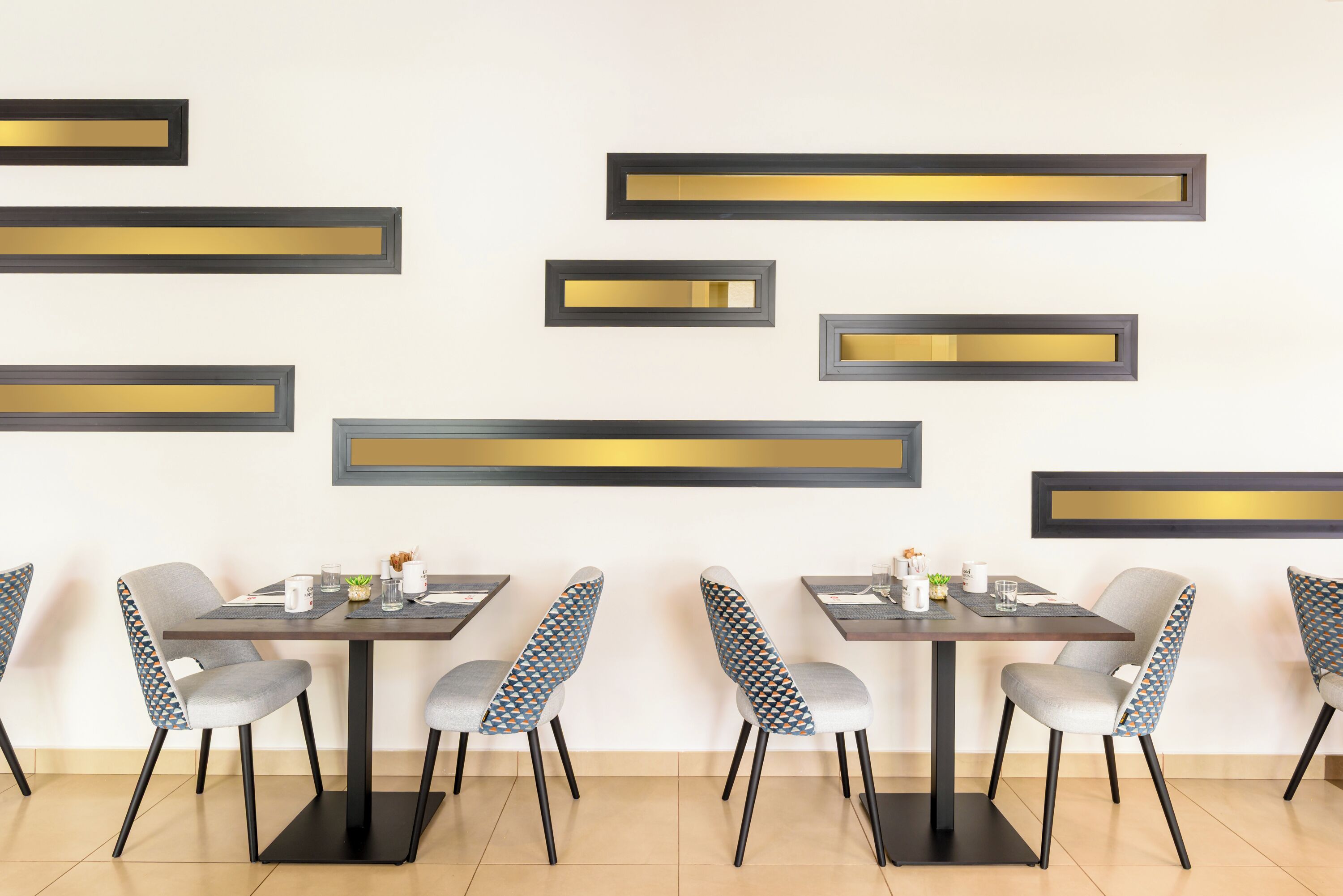 Un comedor moderno con adornos rectangulares en la pared y sillas tapizadas en gris.
