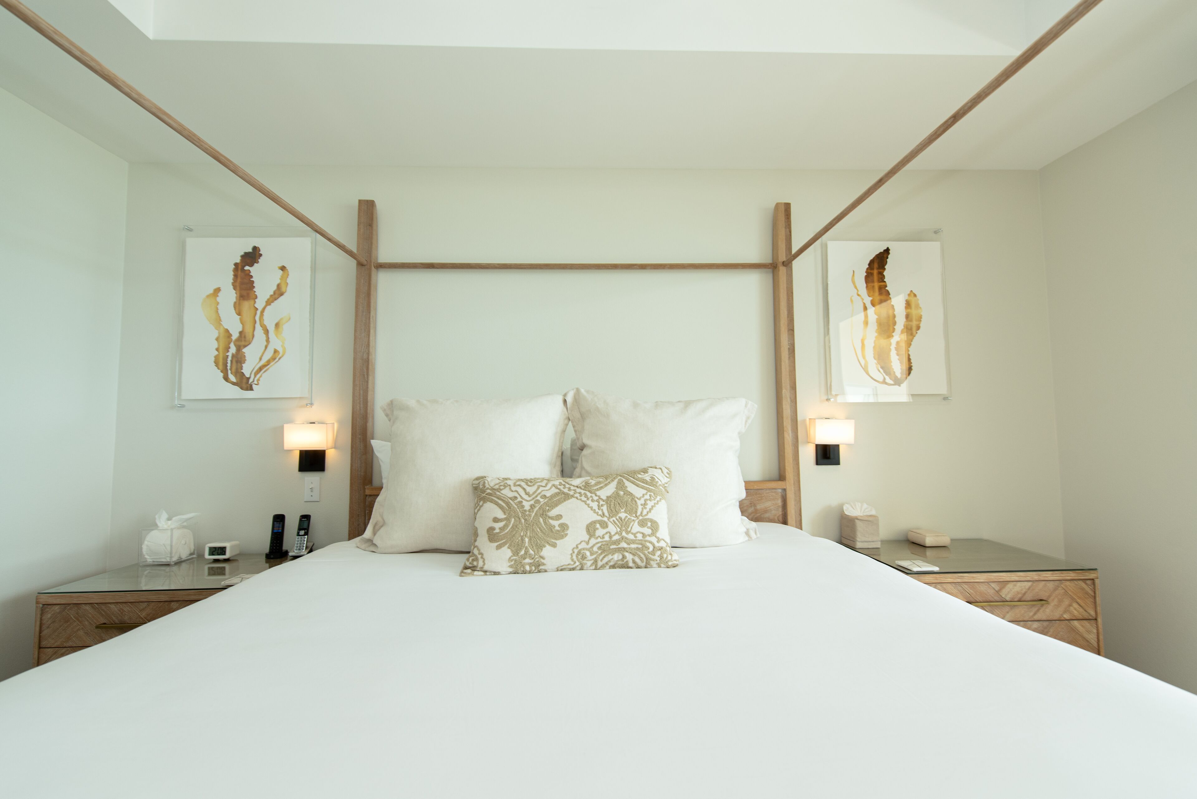 Una habitación de hotel moderna con una cama grande, dos mesitas de noche y obras de arte en las paredes.