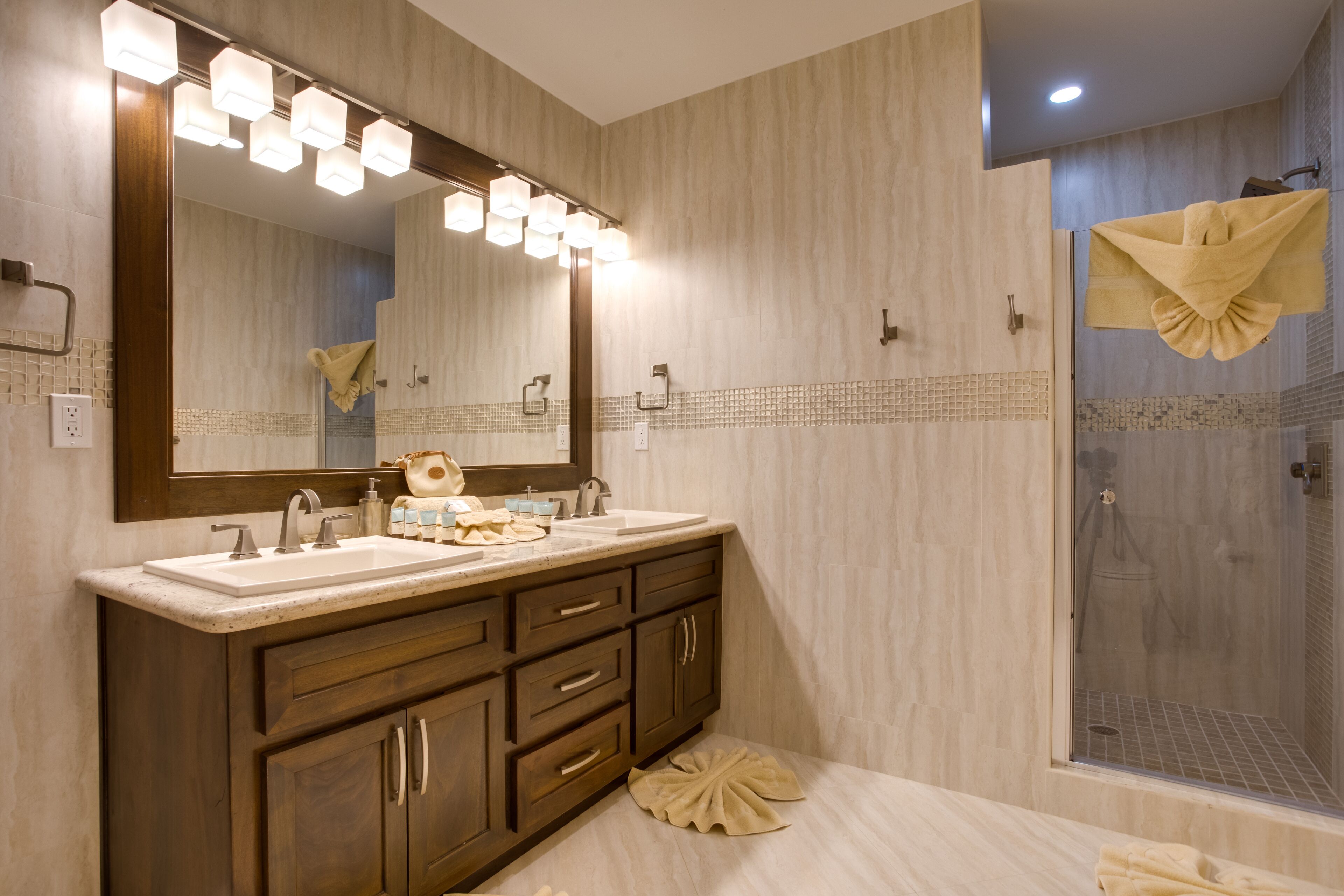 A bathroom with a large mirror, vanity with a sink, and a shower area.