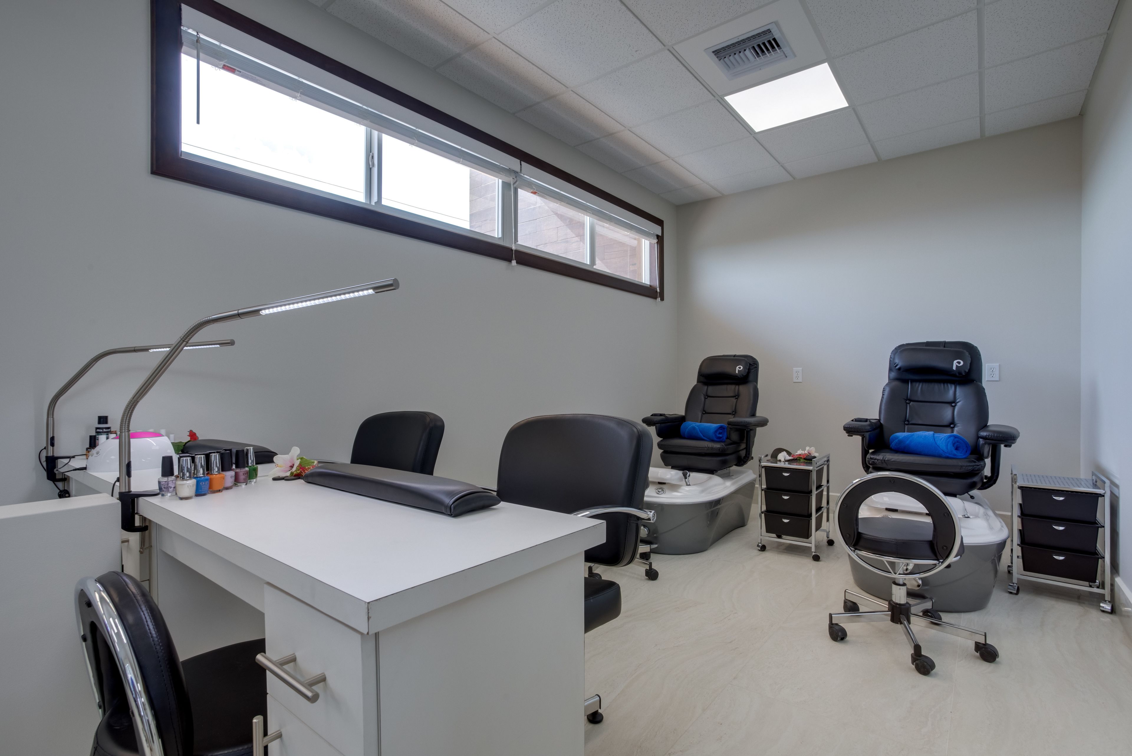 A clean, well-lit room with a desk, chairs, and a foot massage chair.