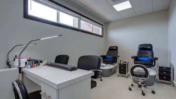A clean, well-lit room with a desk, chairs, and a foot massage chair.
