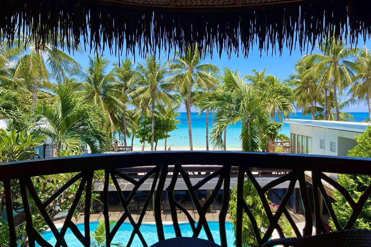 A pool area with a view of the ocean and palm trees.