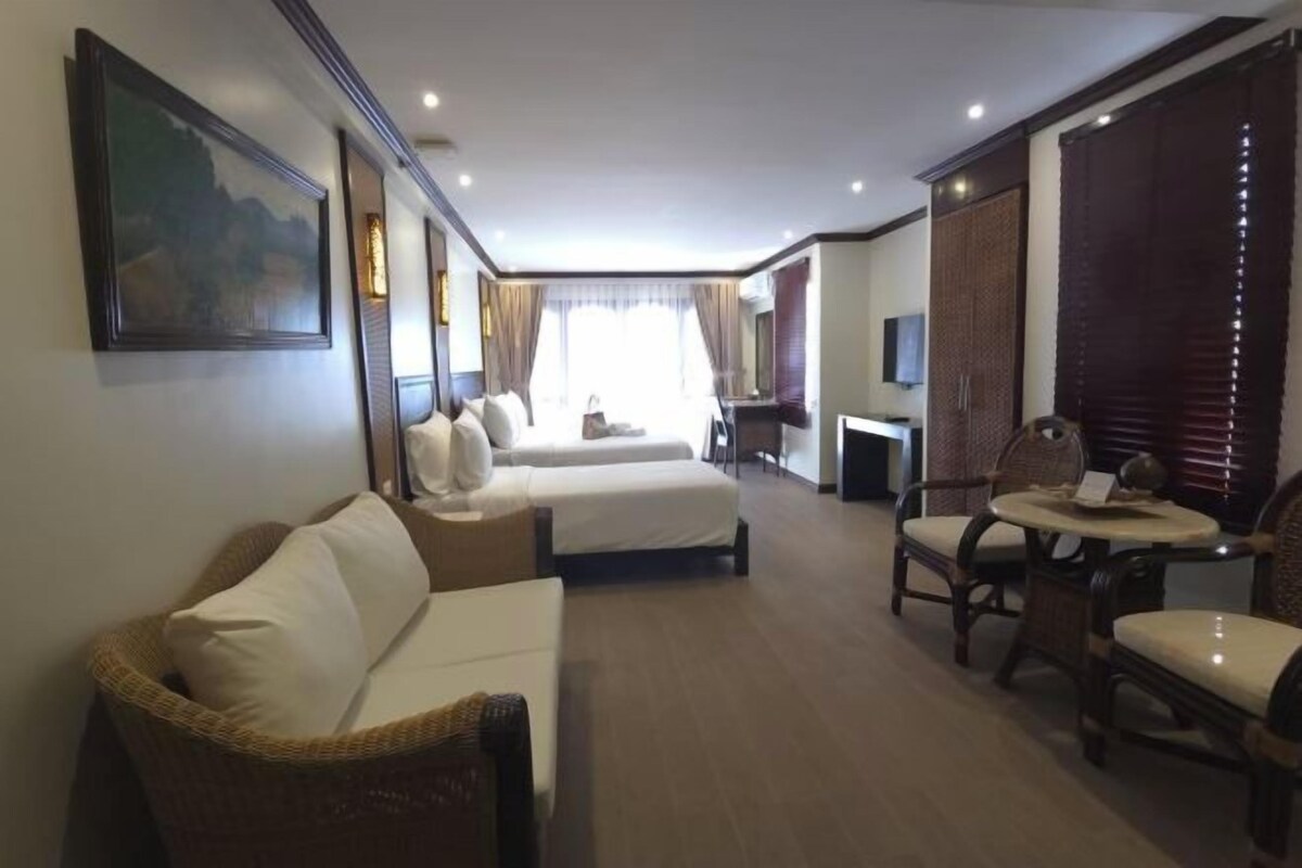 Habitación de hotel con cama, dos sofás, una mesa de comedor y televisor.