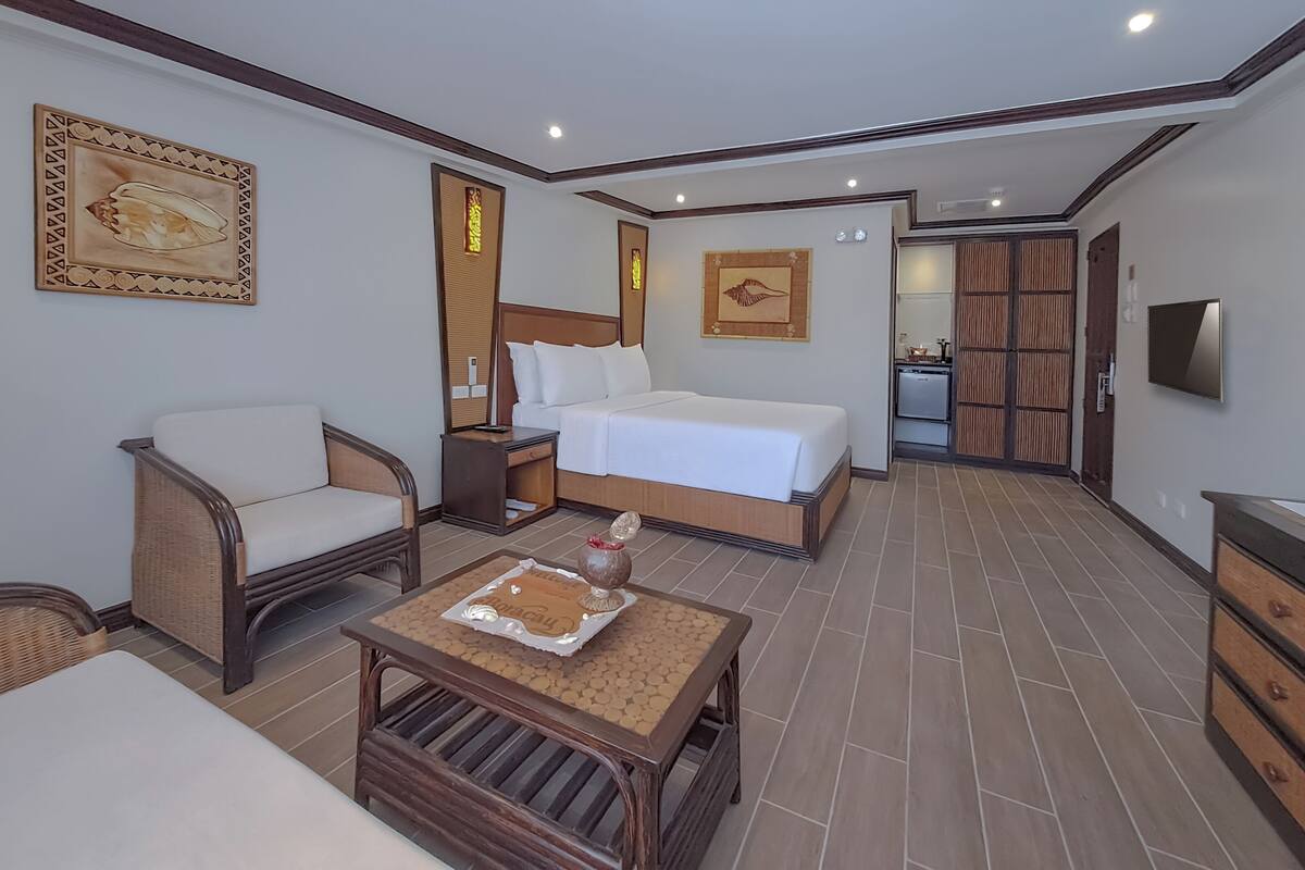 A hotel room with a bed, a chair, a small table, and a television.