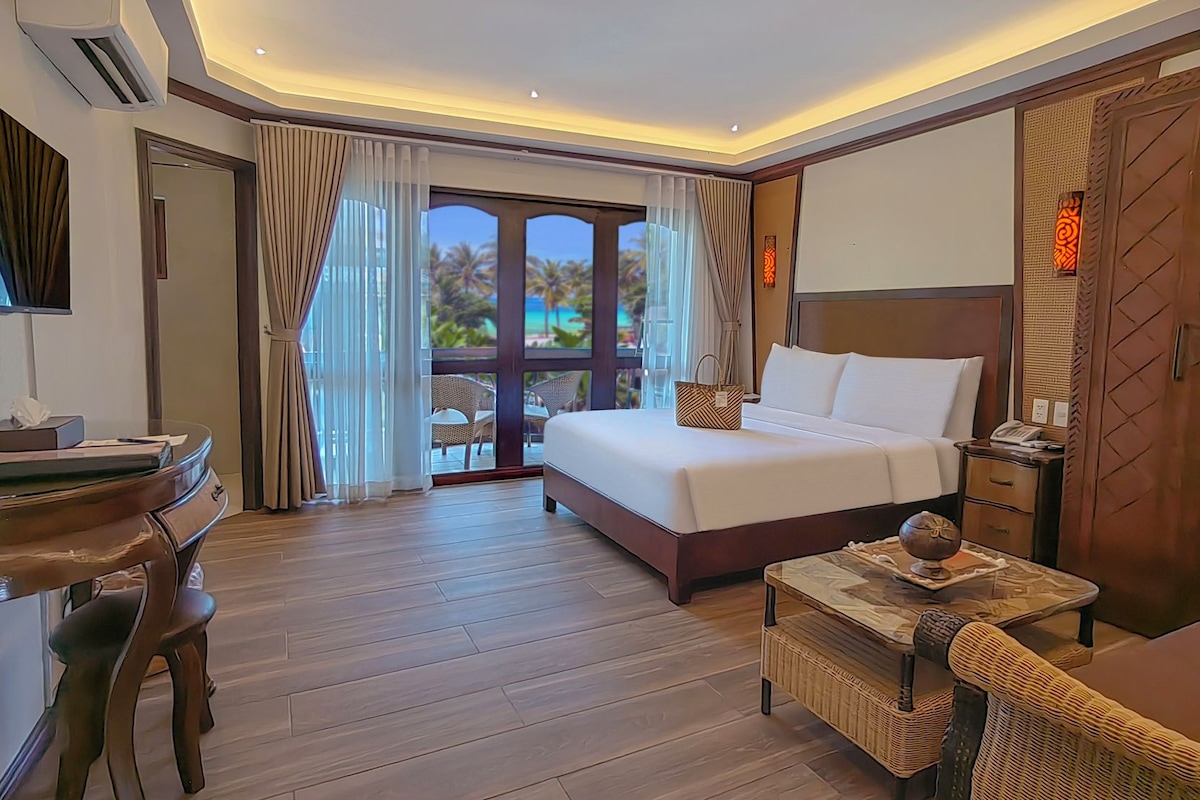 Habitación de hotel con cama, escritorio, silla y vista al exterior.