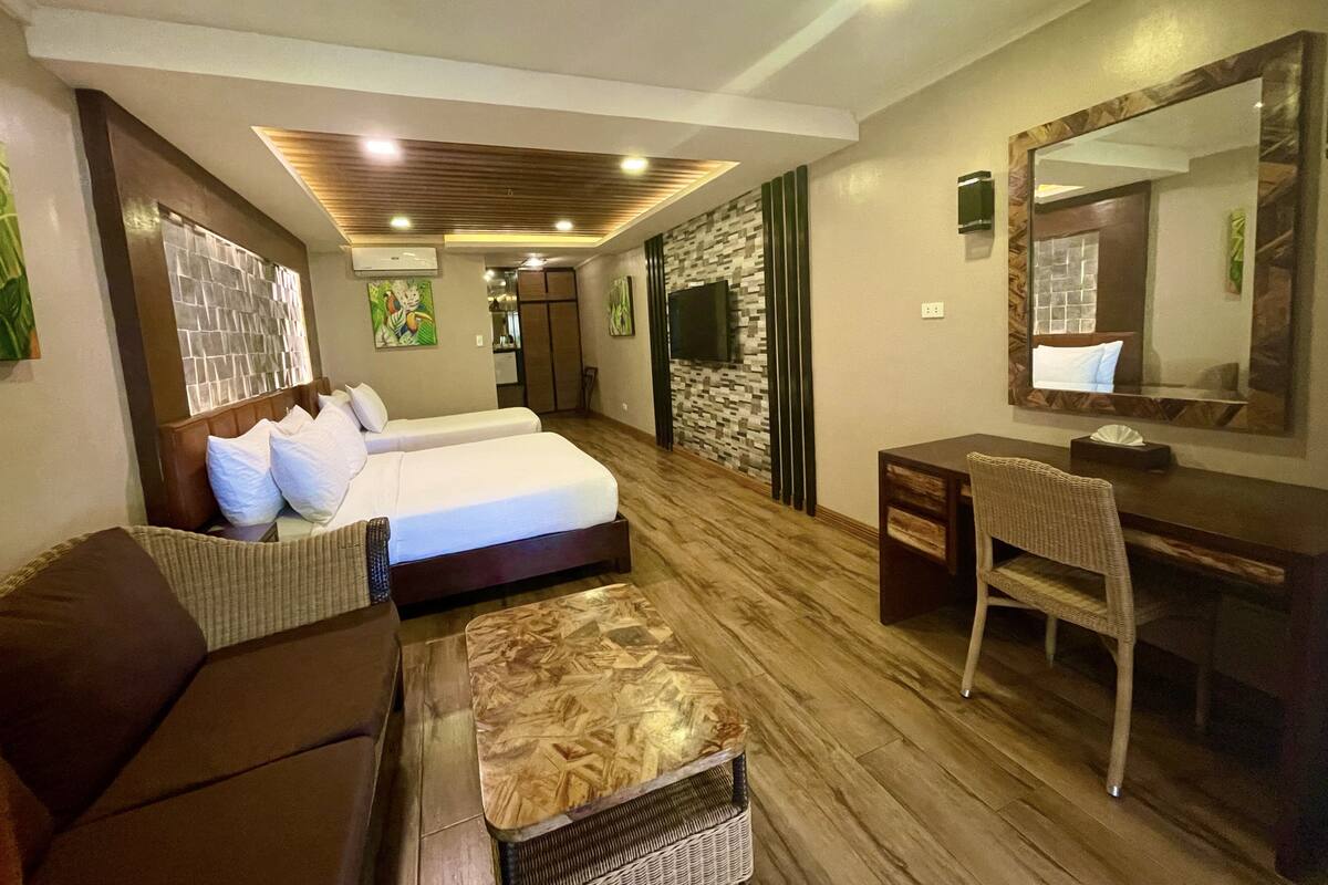 A hotel room with a bed, a sofa, a desk, and a chair.