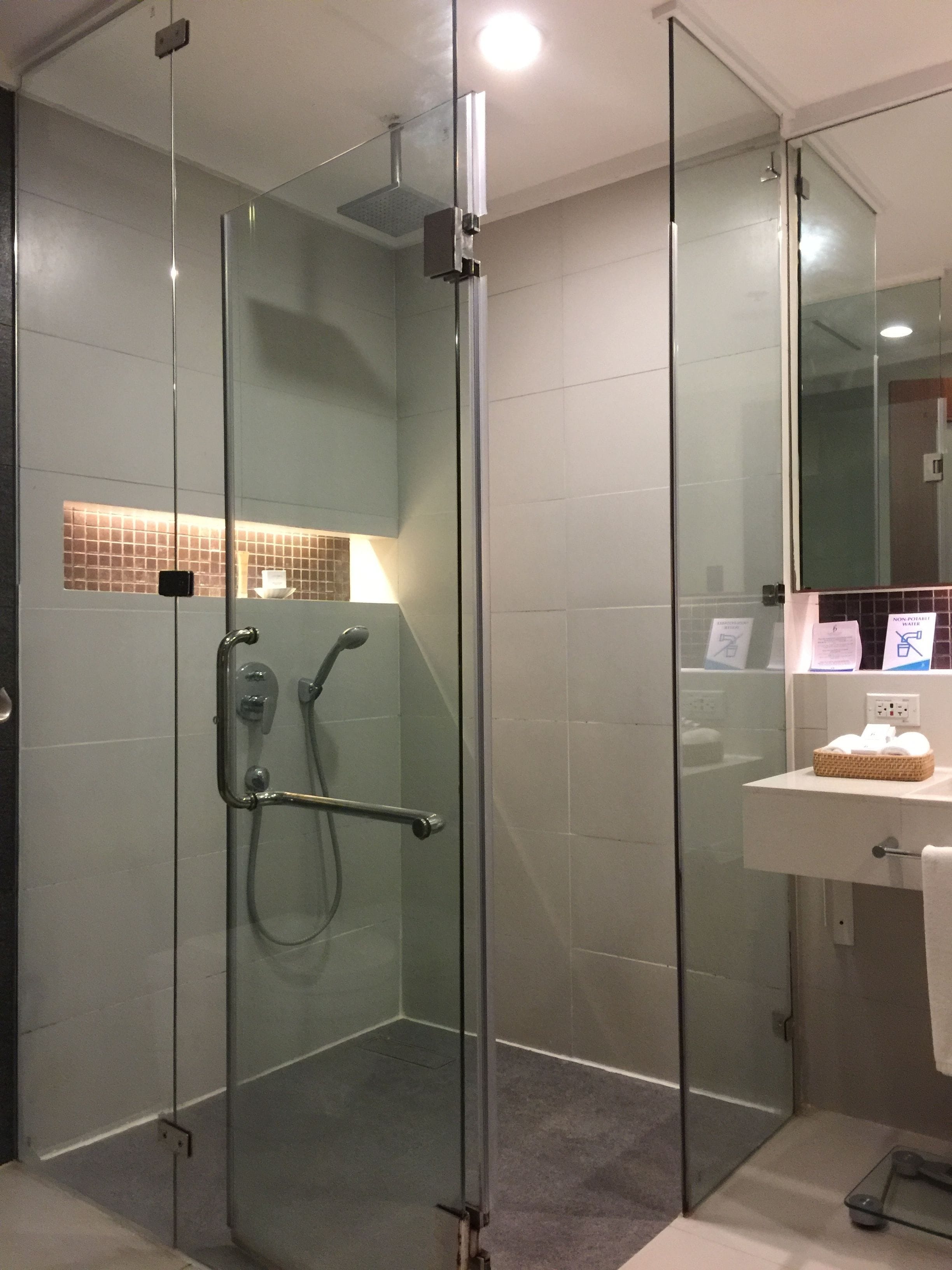 Une salle de bain moderne avec une douche à parois de verre, un lavabo blanc et un miroir au-dessus.