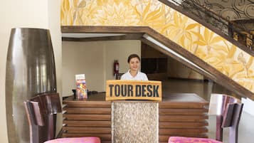 Un mostrador de información turística con un letrero de madera, un extintor y una escalera con un fondo de papel tapiz floral.