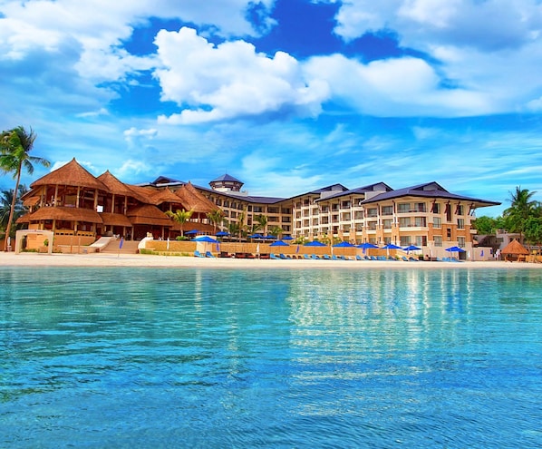 Un resort con varias edificaciones, playa y piscina.