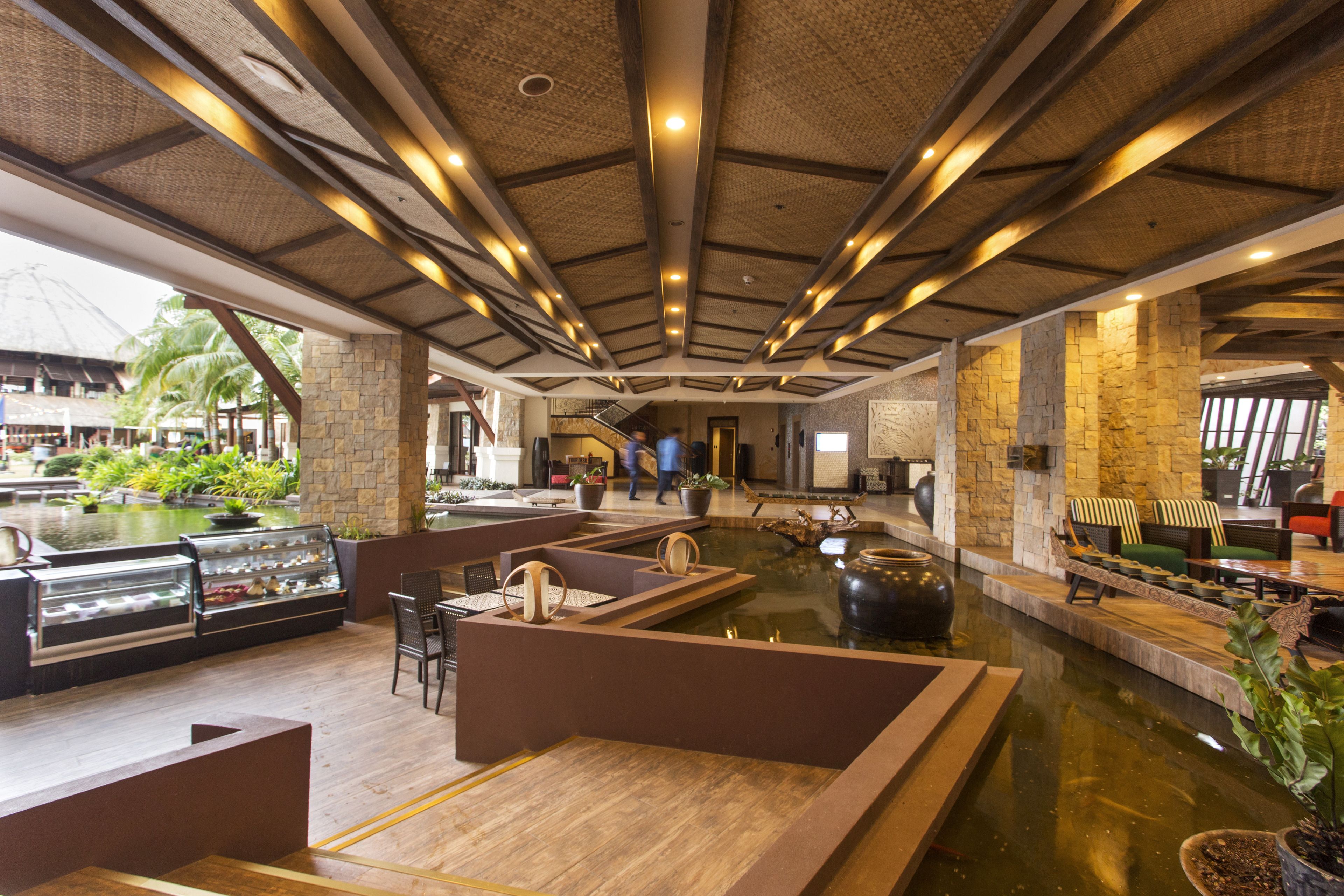 A spacious lobby with a central water feature, stone walls, and modern seating areas.