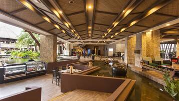 A spacious lobby with a central water feature, stone walls, and modern seating areas.