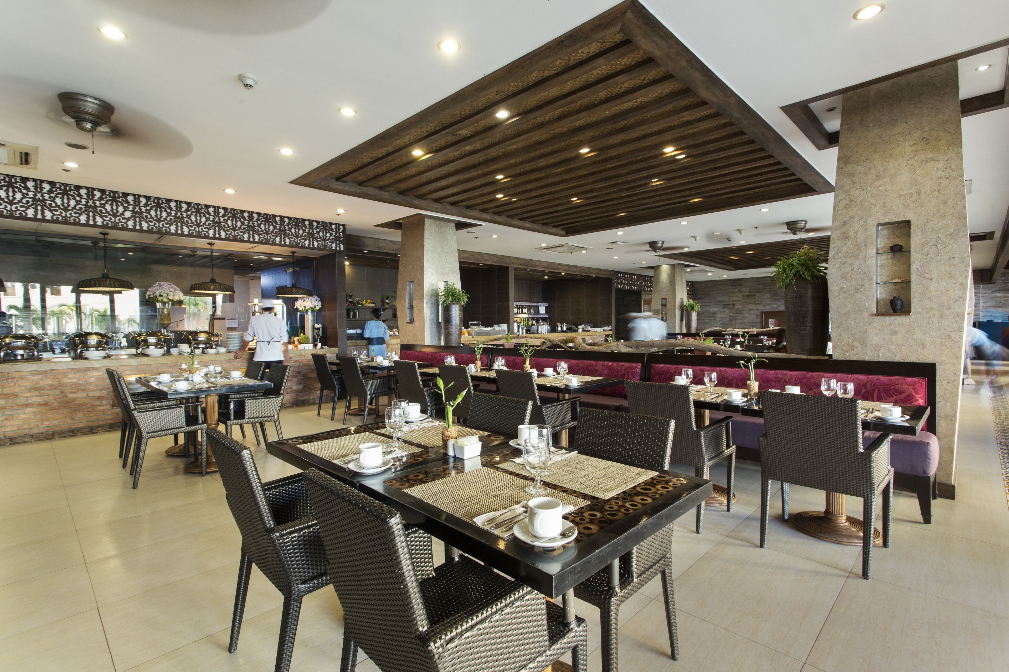 Un restaurante espacioso con techos altos, iluminación moderna y diversas opciones de asientos, incluyendo mesas y cabinas.