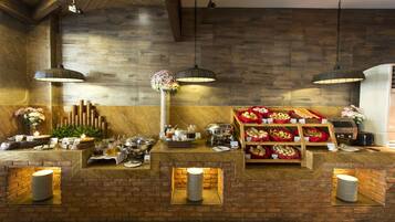 A breakfast buffet area with a brick wall, hanging lights, and a variety of food and drink options.