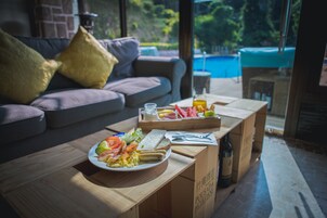 Una mesa de comedor con un plato de comida, una botella y una bandeja con frutas y verduras.