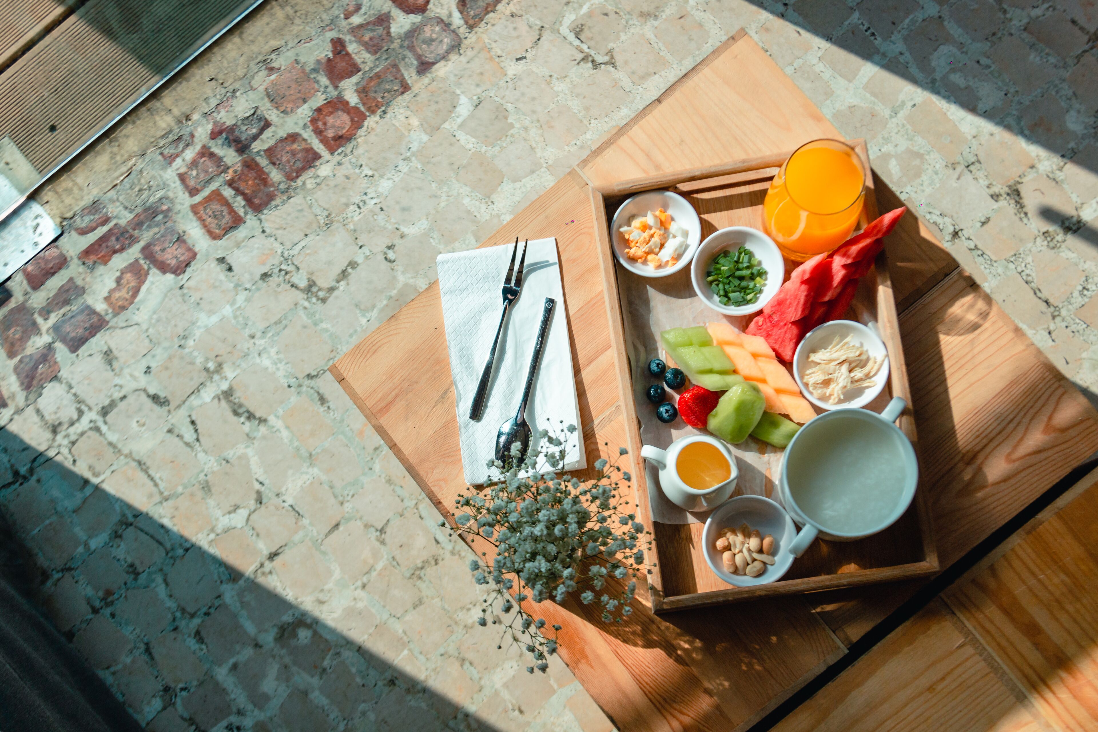 Una bandeja de madera con frutas, verduras y bebidas sobre una mesa.