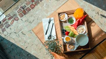 Una bandeja de madera con frutas, verduras y bebidas sobre una mesa.