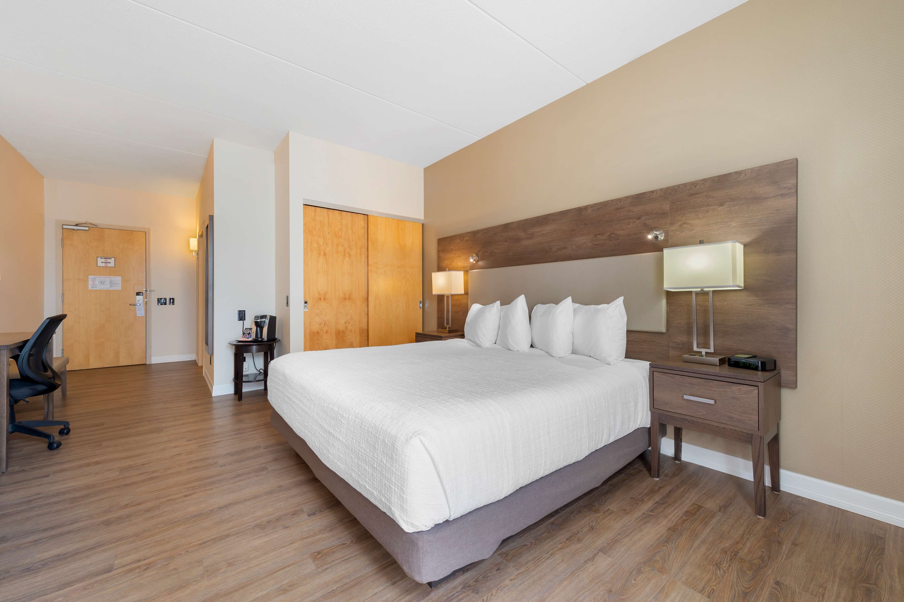 A hotel room with a large bed, bedside tables, a desk, and a chair.