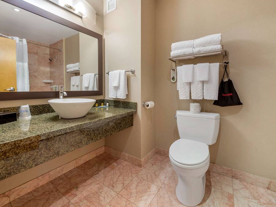 A bathroom with a sink, mirror, toilet, and towel rack.
