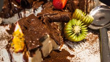 Une assiette à dessert avec de la glace enrobée de chocolat, des fraises, des tranches de kiwi et une cuillère.