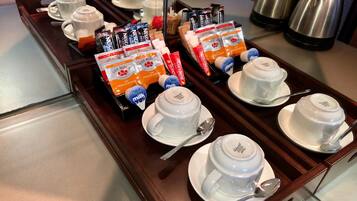 Un carretó de buffet per esmorzar amb tetreres, tasses i platets blancs, a més de diverses seleccions de menjar i beguda.