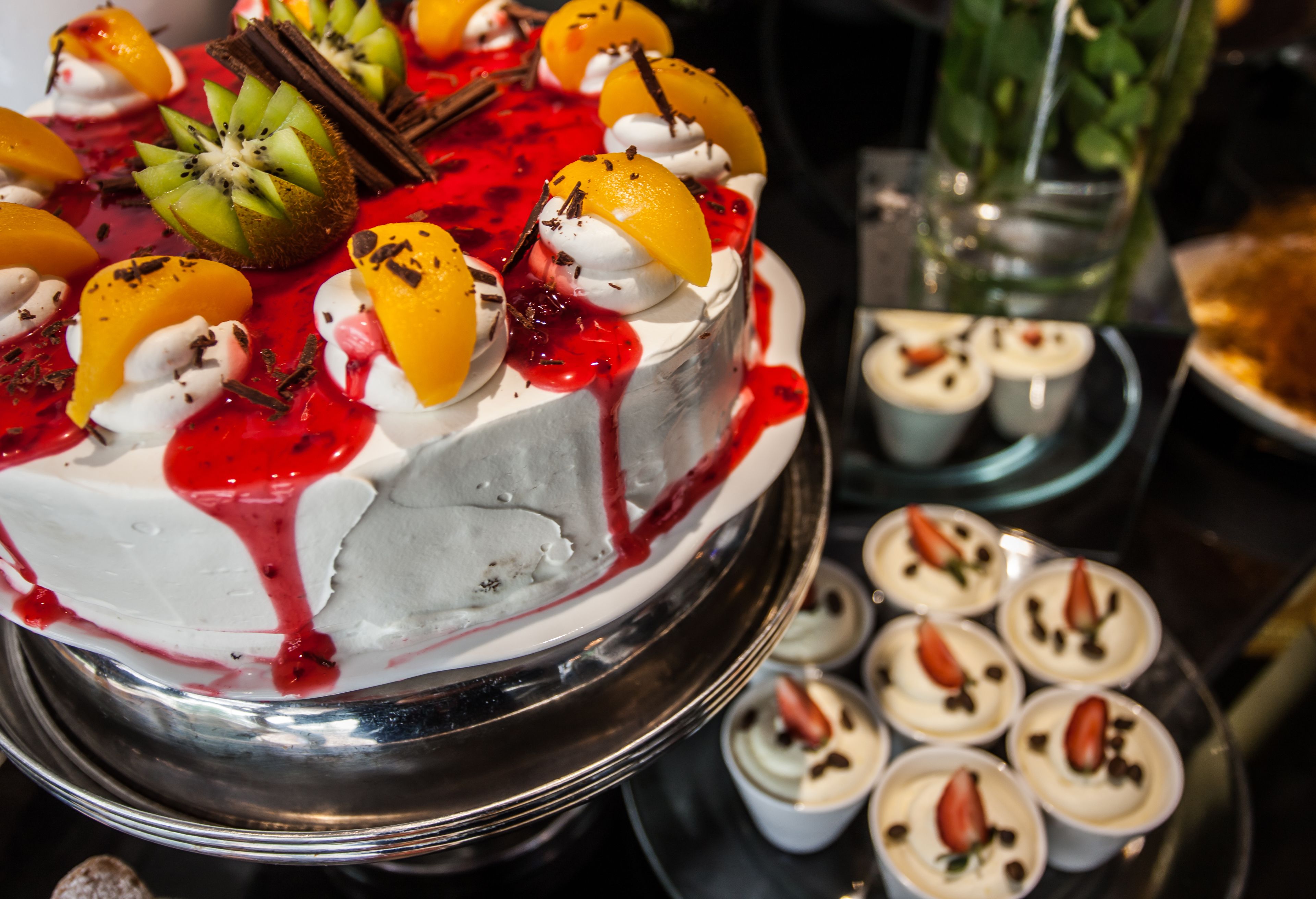 A dessert display with a cake, fruit, whipped cream, and chocolate decorations.