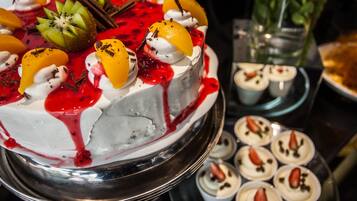 A dessert display with a cake, fruit, whipped cream, and chocolate decorations.