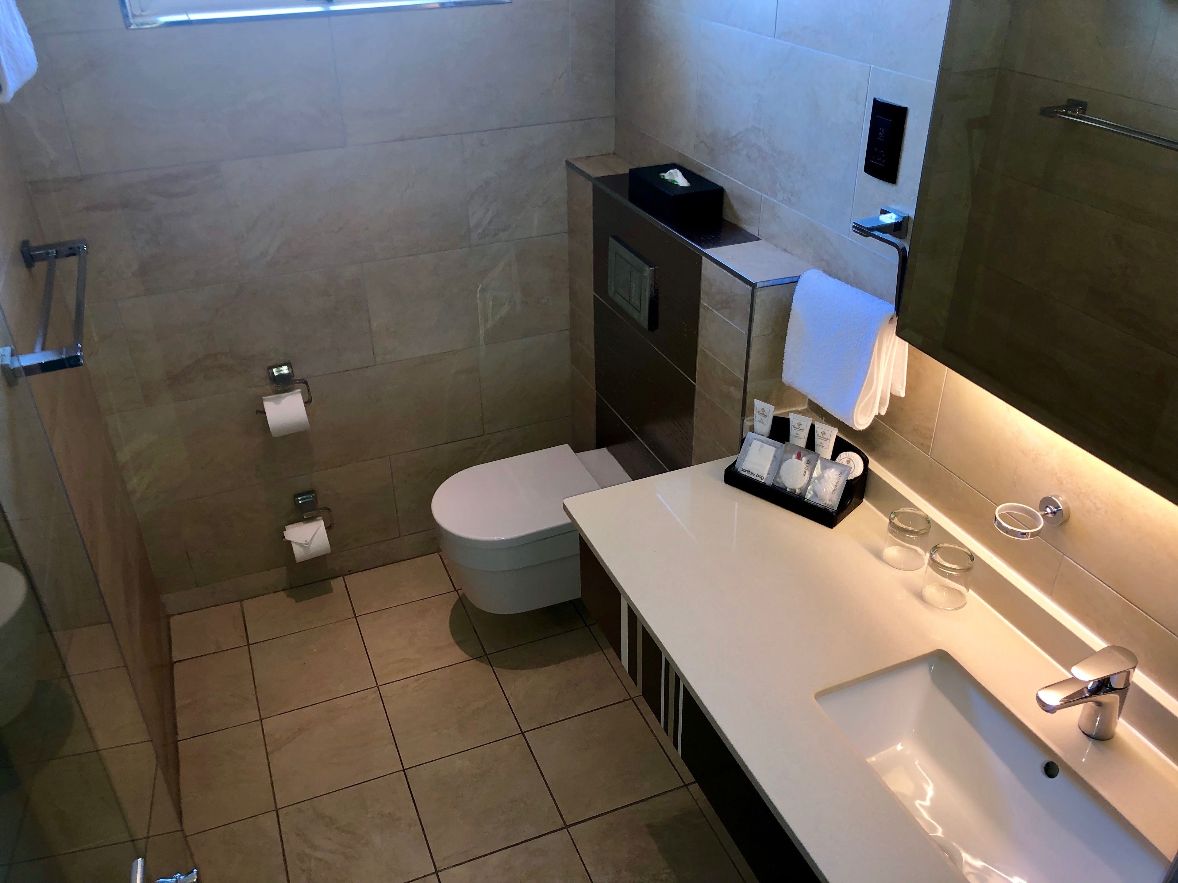 Ein modernes Badezimmer mit Toilette, Waschbecken und Spiegel.