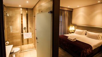 A hotel room with a shower, toilet, and a bed with a headboard.