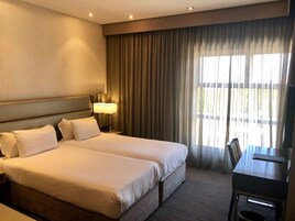 A hotel room with two beds, a desk, and a TV.