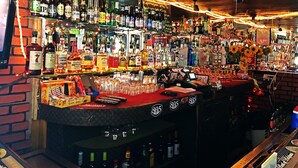A bar with shelves of various liquor bottles, glasses, and a cash register. - Patio Motel (Gardena)
