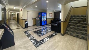 A hotel lobby with a reception desk, vending machines, a black leather sofa, and a patterned carpet. - Patio Motel (Gardena)