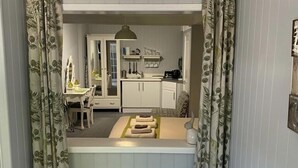 A compact kitchen with white cabinets, a countertop, and a radiator.