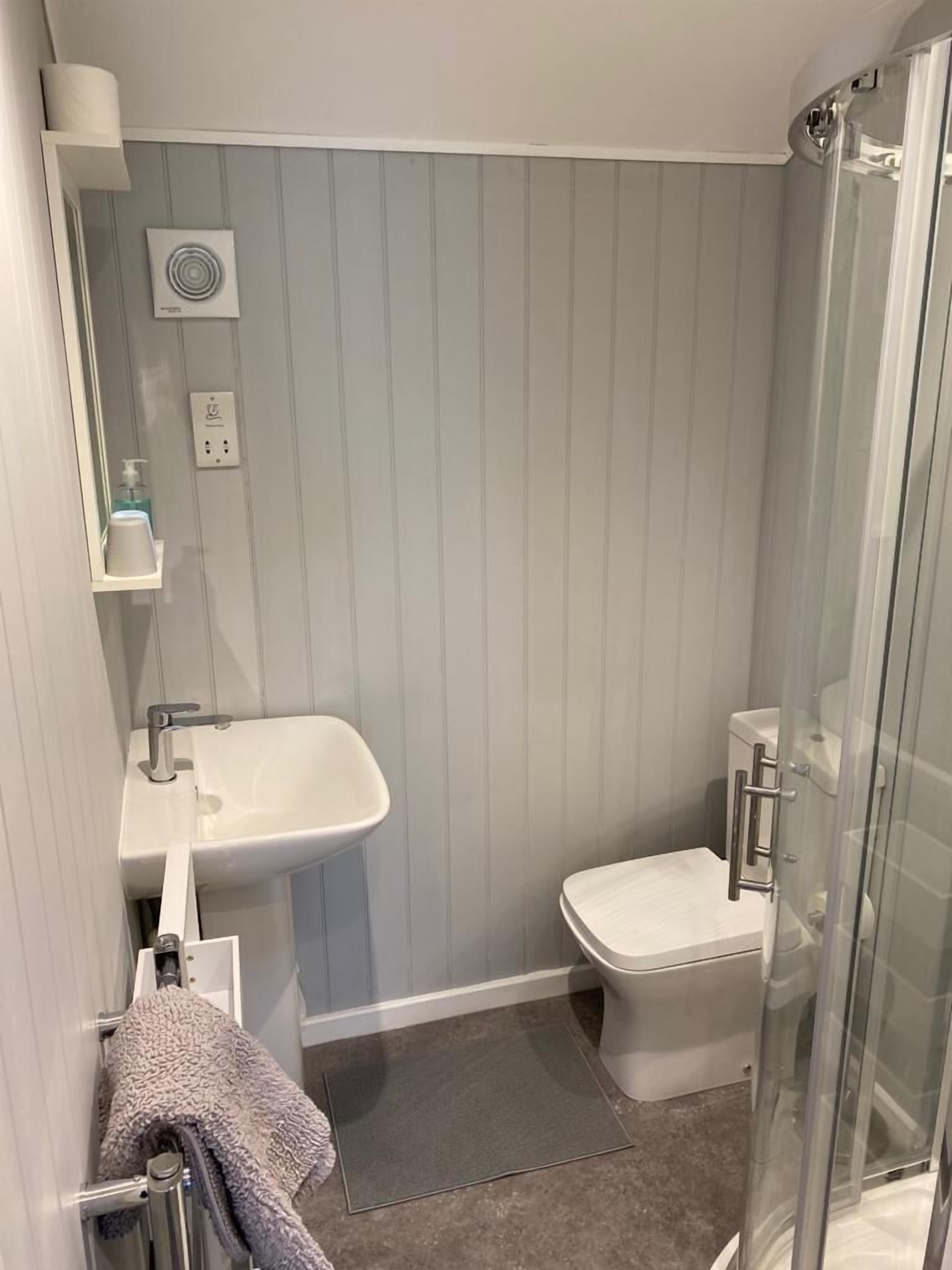 A bathroom with a white sink, a toilet, a glass shower enclosure, and a towel rack.