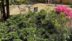 A backyard with a wooden fence, outdoor furniture, and various plants.