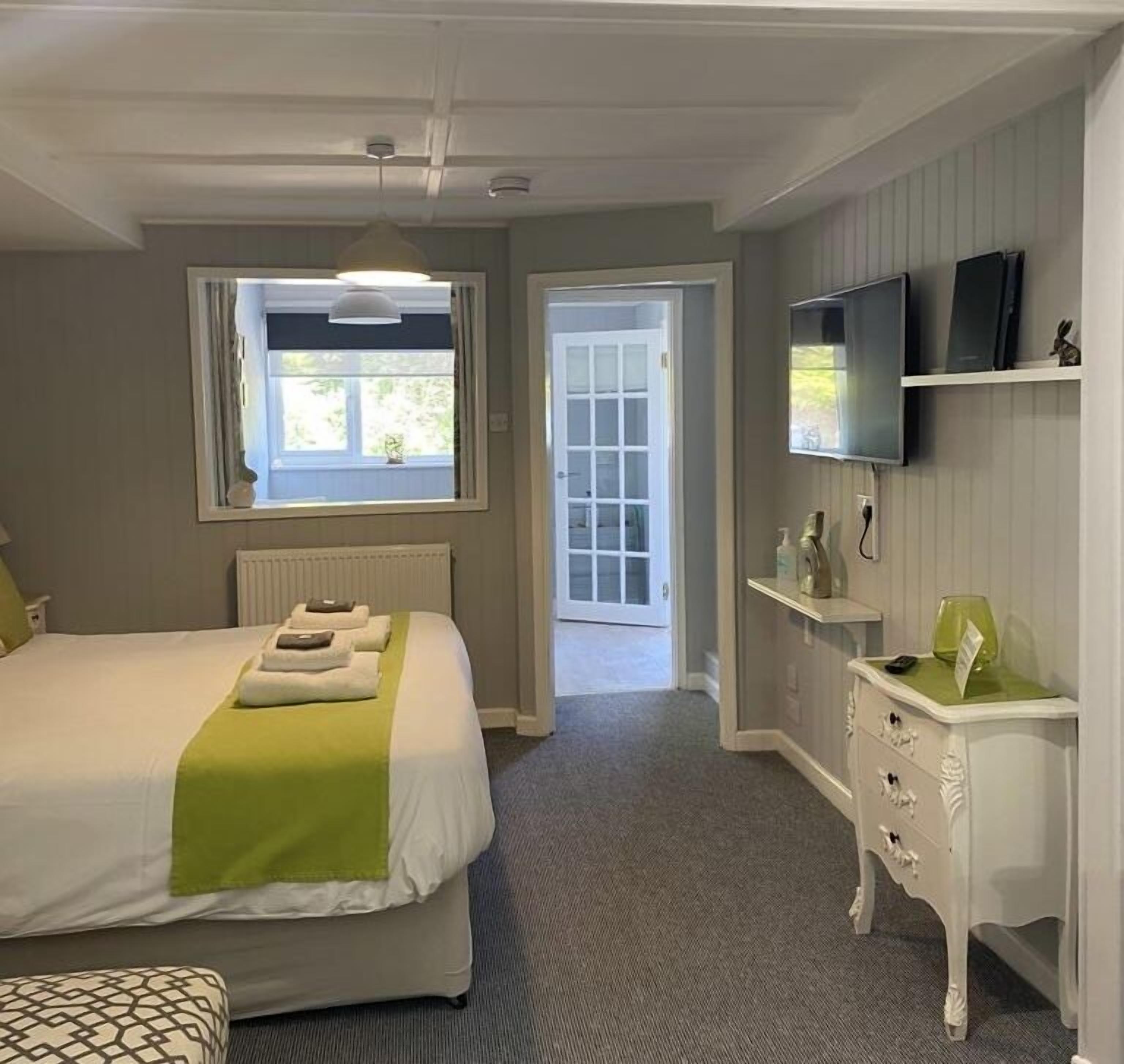 Una habitación de hotel con cama, televisor, escritorio y ventana.