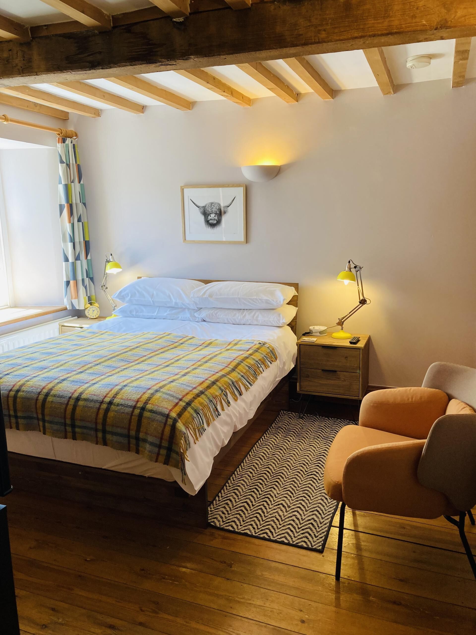 Un dormitorio con cama, mesitas de noche, lámpara, silla, alfombra y ventilador de techo.