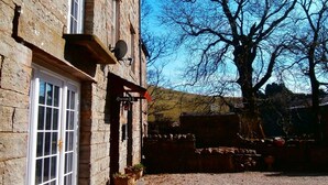 A stone building with a gravel driveway, a white door, and a window. - Riverside B & B (Leyburn)