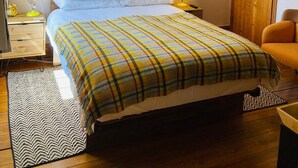 A bedroom with a bed, two bedside lamps, a framed picture on the wall, and a wooden door. - Riverside B & B (Leyburn)