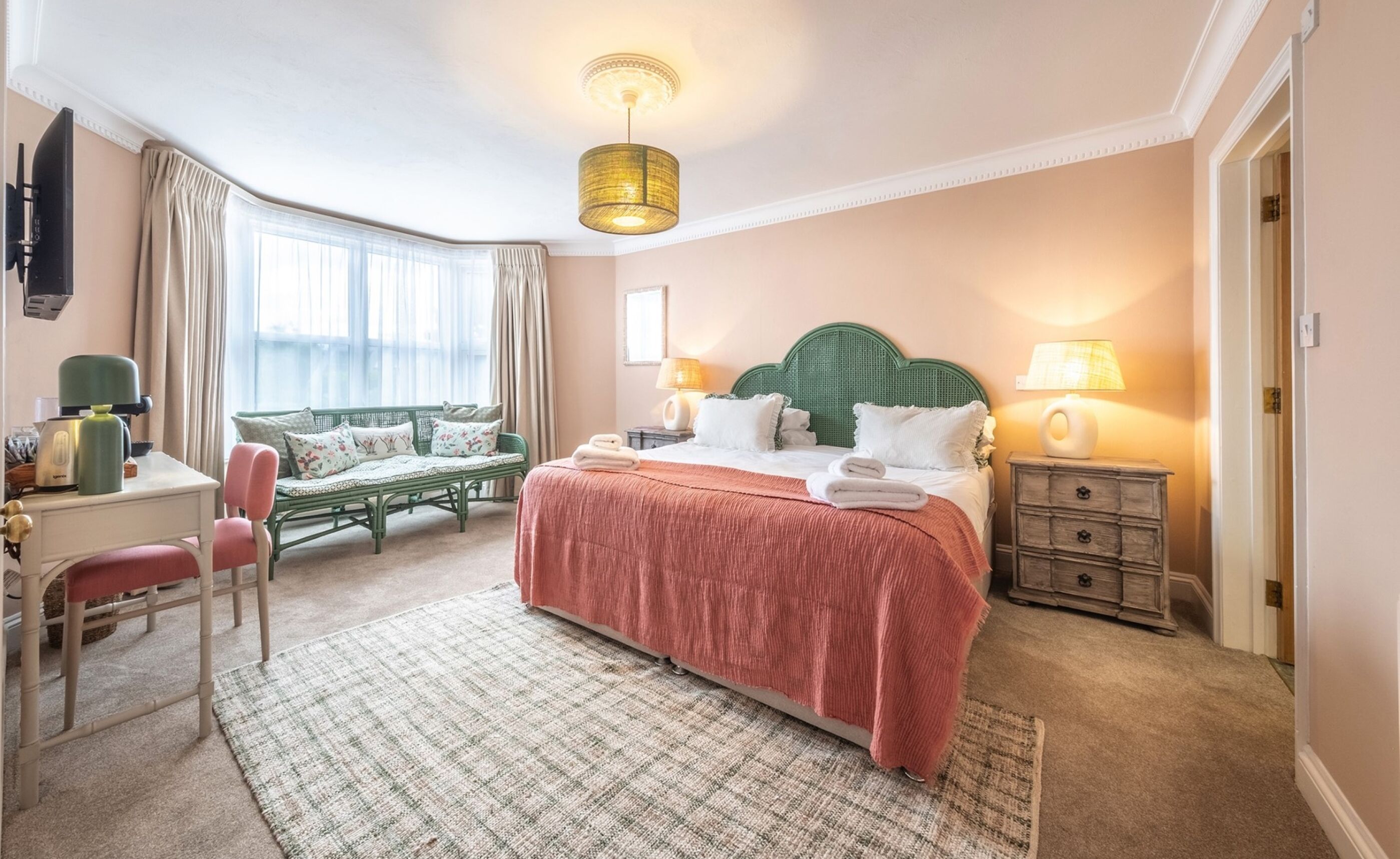 A hotel room with a bed, a desk, a chair, a sofa, and a television.