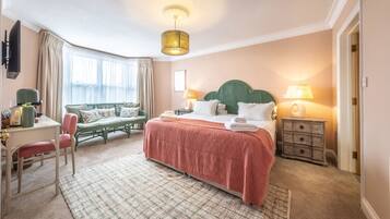 Una habitación de hotel con cama, escritorio, silla, sofá y televisor.