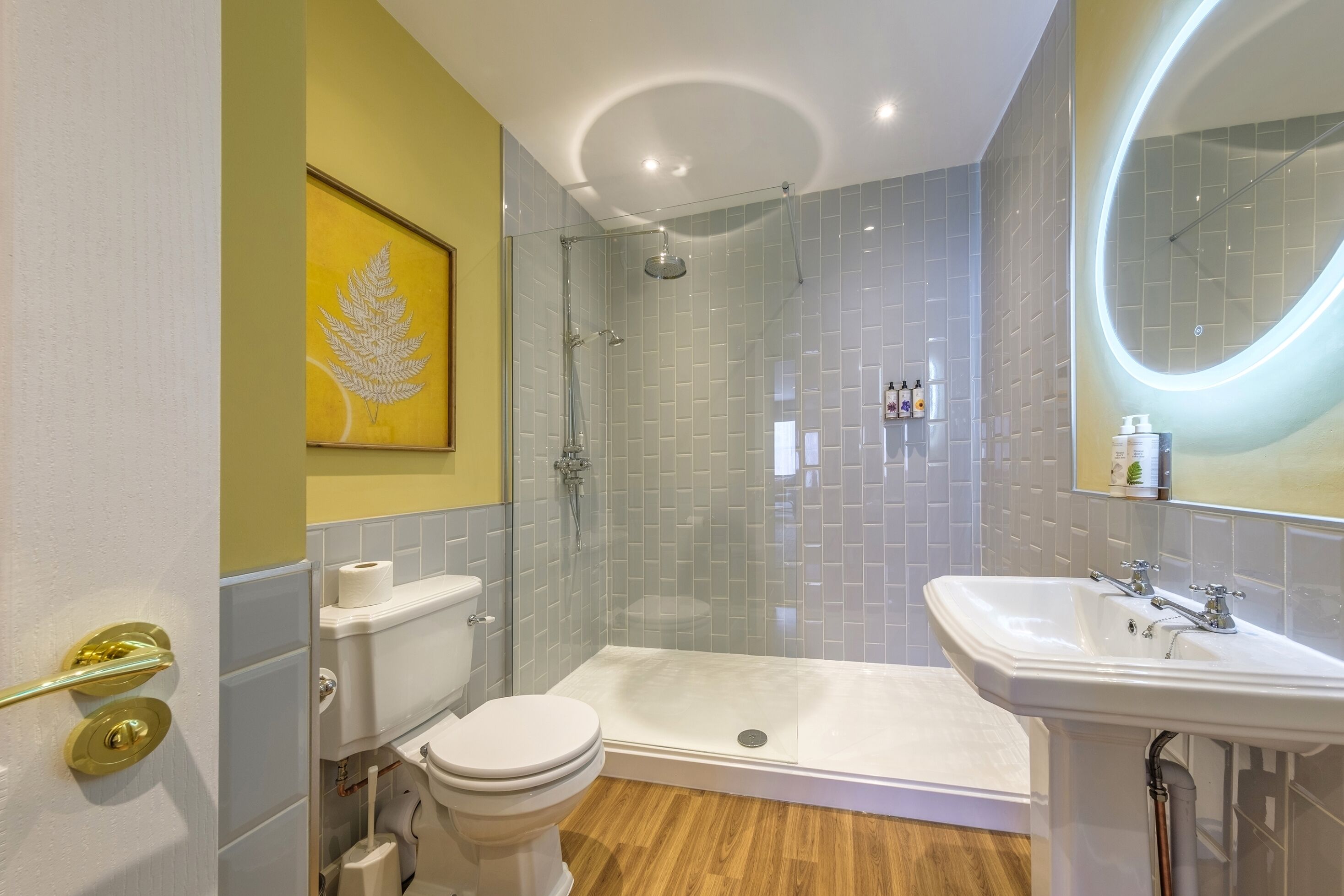 A modern bathroom with a glass-enclosed shower, a white toilet, and a sink.