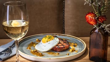 A plate of food with a glass of wine and a vase of flowers on a table.