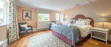 A bedroom with a bed, bedside tables, a chair, a window with curtains, and a radiator.