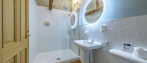 A bathroom with a shower, sink, toilet, and wooden door.