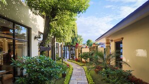 A narrow stone pathway flanked by lush greenery and potted plants, leading to a building with a sign reading "Pool & Spa". - Atithi Resort & Spa (Pokhara)